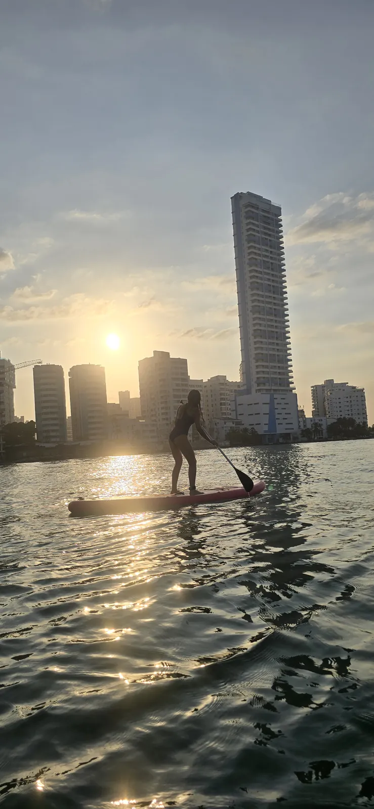 Silueta paddleando frente al skyline al amanecer
