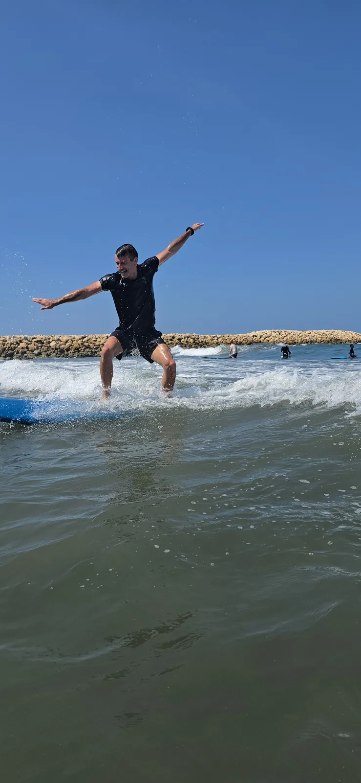 Surfista haciendo popup con los brazos abiertos junto al espolón